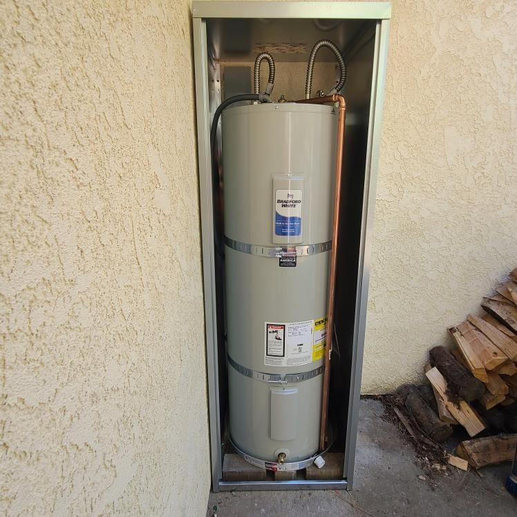 Water heater enclosed in a metal frame, mounted on an exterior wall.