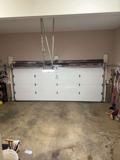 White garage door in a garage, with a garage door opener above.
