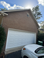 Brick building with white garage door; sun shining behind clouds.