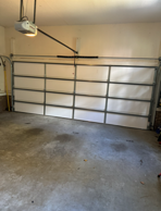 Garage interior with closed white door and concrete floor. Garage door opener visible.