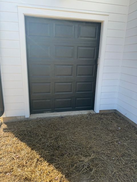 Black garage door with white trim on a building with white siding.