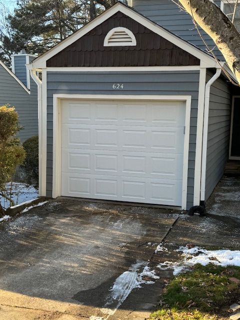 Garage with white door, blue siding, brown trim, and address 