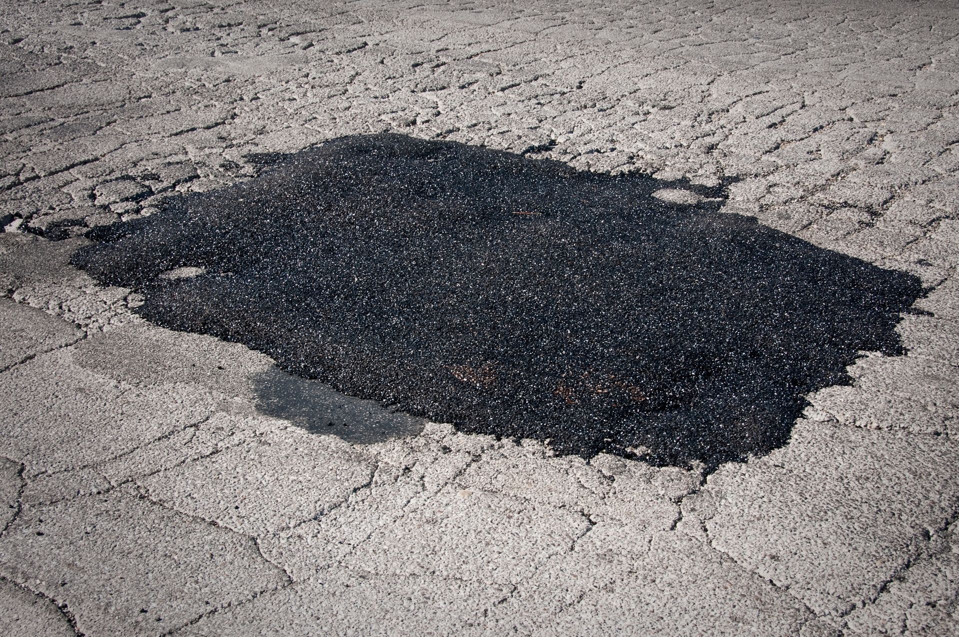 A large hole in the asphalt on the side of a road.
