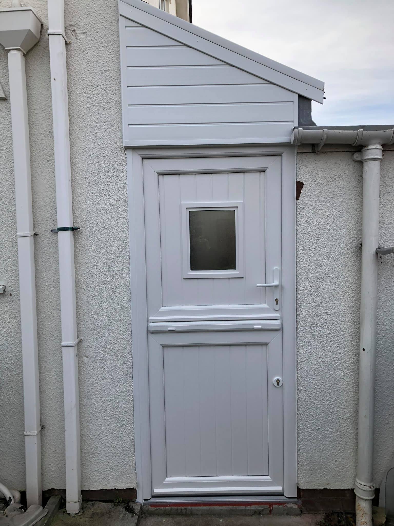 A white door with a small window on the side of a building.