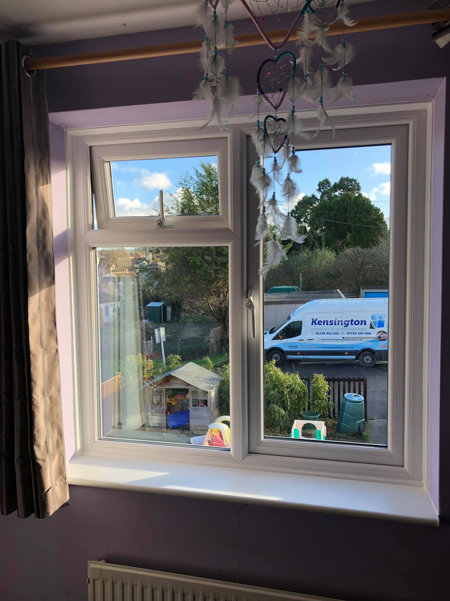 A white van is parked in front of a window in a room.