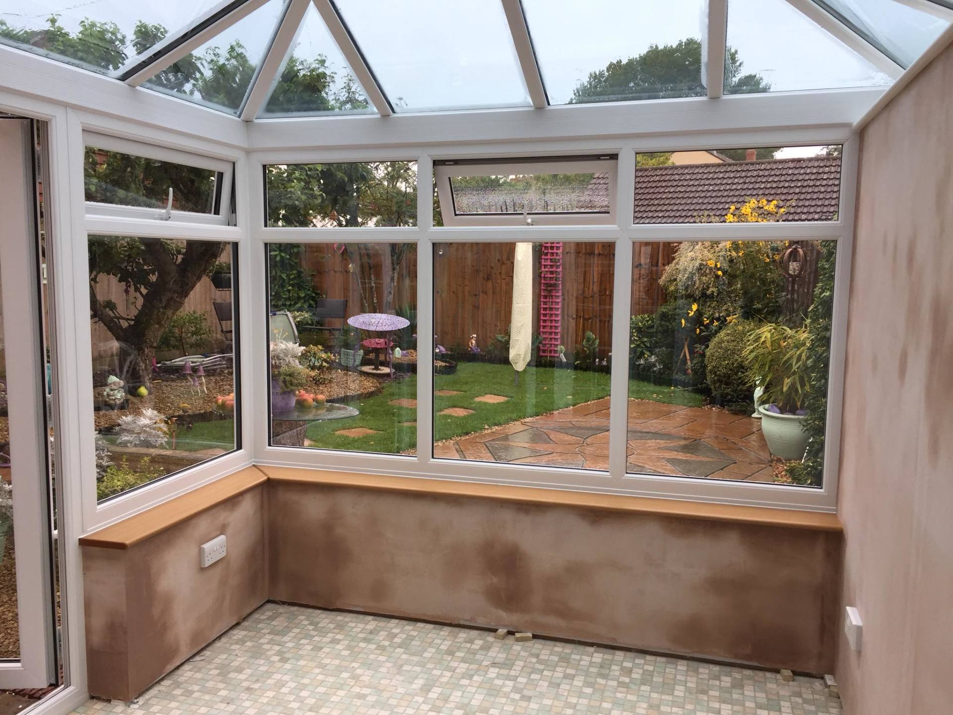 A conservatory with a lot of windows and a view of a garden.