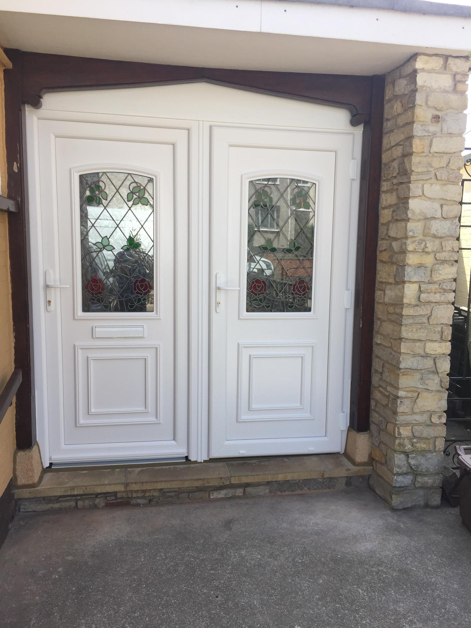A white door with a stained glass window is sitting on the side of a building.