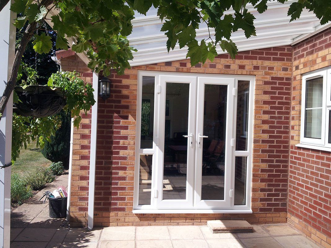 A brick house with white french doors and windows