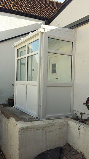 A white building with a window and a door on the side of it.