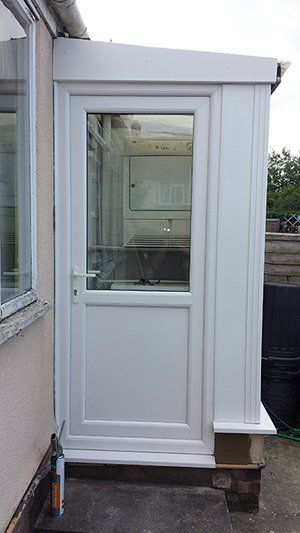A white door with a glass window is on the side of a house.