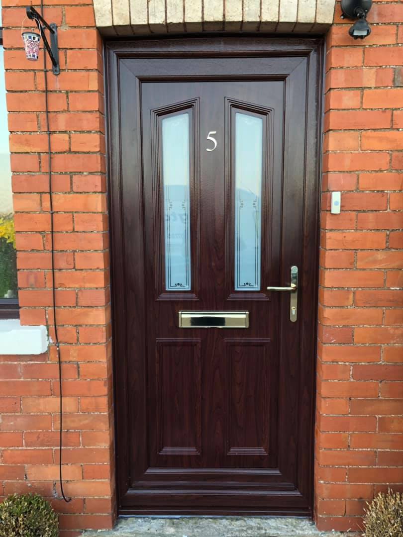 A brown door with the number 5 on it is on a brick wall.