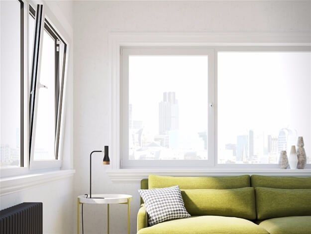 A living room with a green couch and a window.