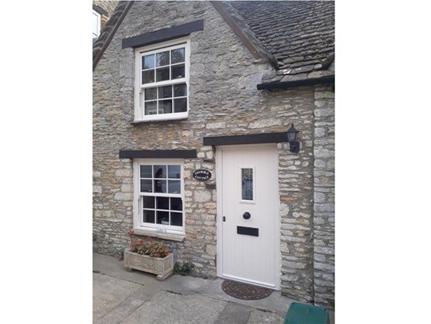 A stone house with a white door and two windows.