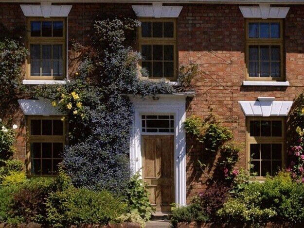 A brick house with a wooden door and lots of windows