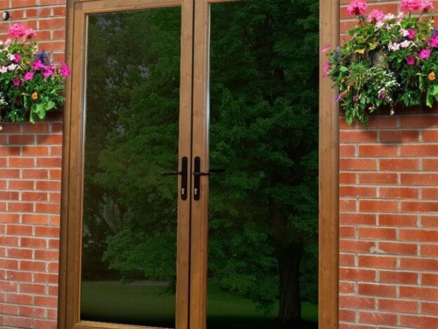A brick building with a wooden door and flowers on the side.