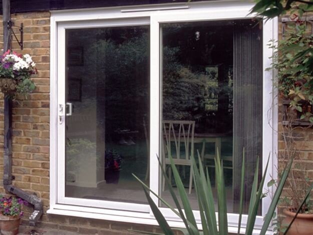 A white sliding glass door is open to a dining room.