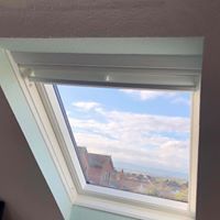 A skylight with a view of a city and a blue sky.