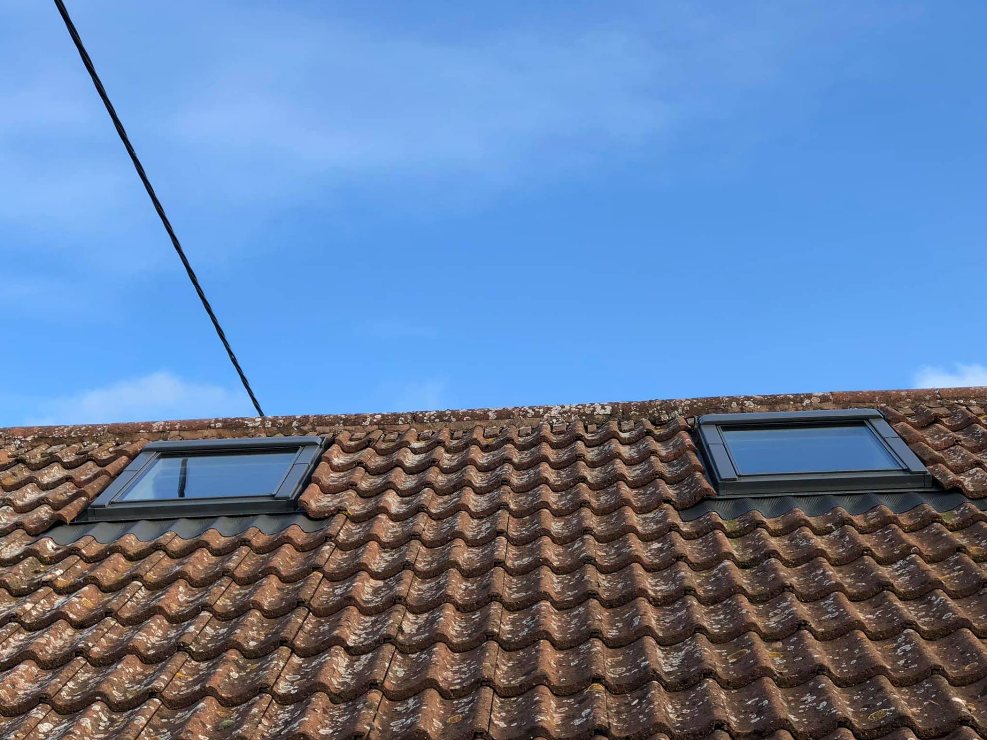 A roof with two skylights on it and a blue sky in the background.