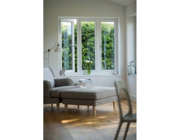 A living room with a chair and ottoman in front of a window