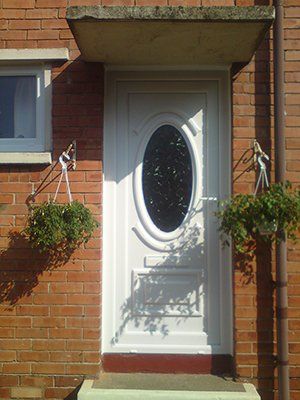 A white door with an oval window on a brick building