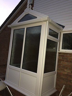 A white porch with a window on the side of a house.
