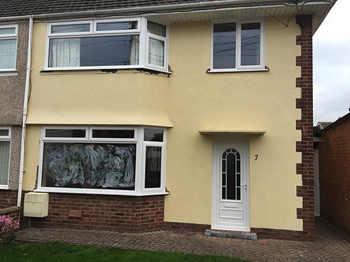 A yellow house with white windows and a white door.