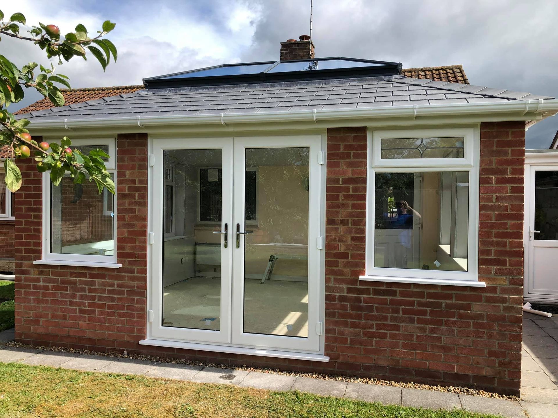 A red brick house with white windows and sliding glass doors.