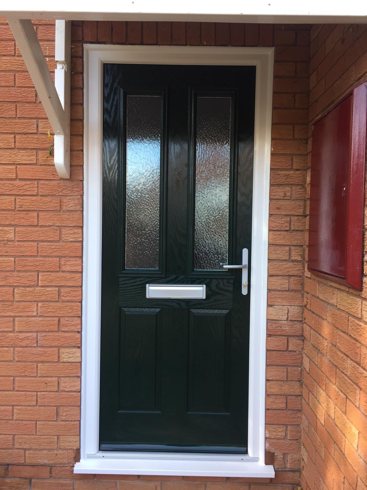 A black door with a white trim is on a brick wall.