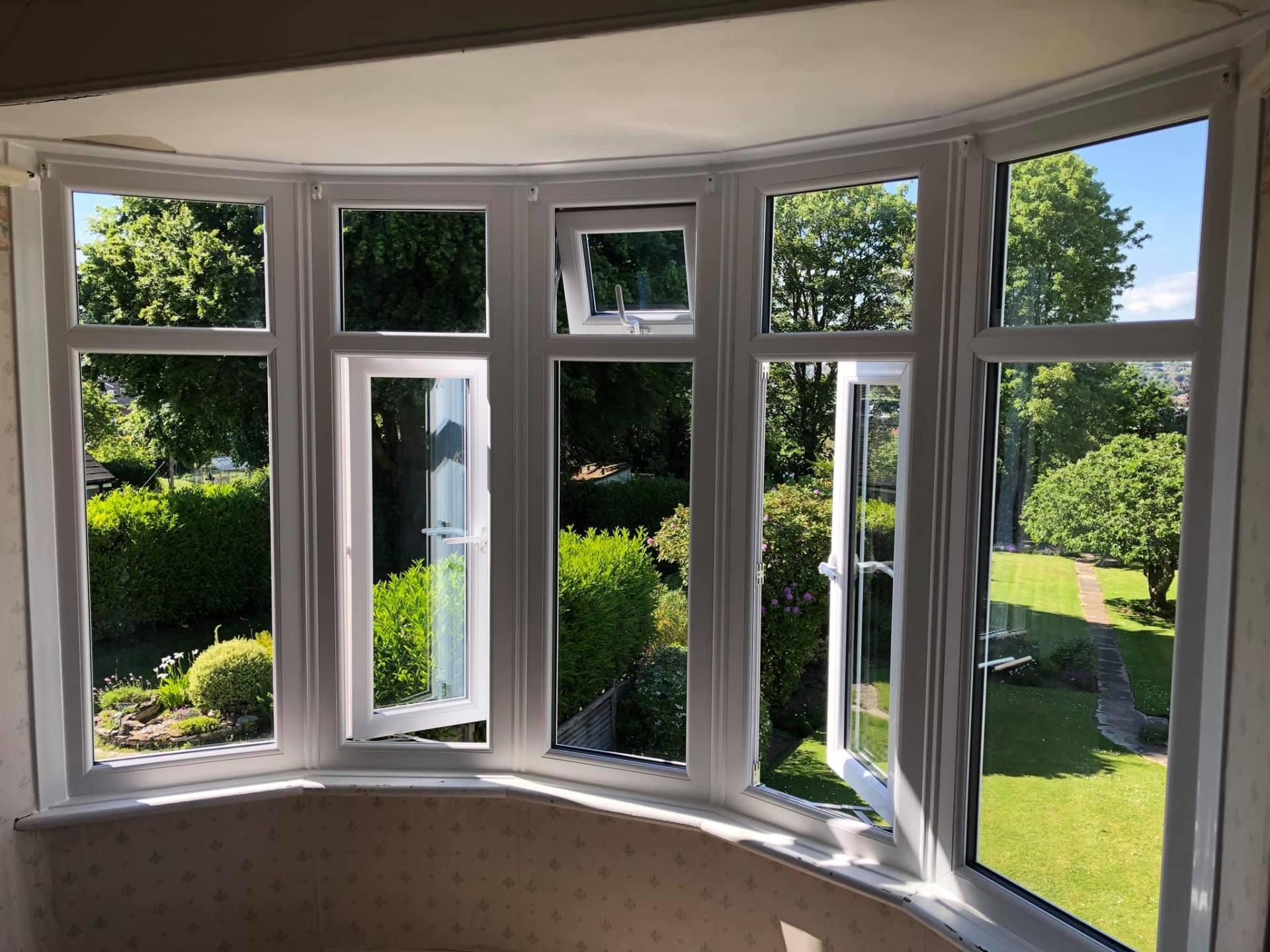 A room with a lot of windows and a view of a garden.