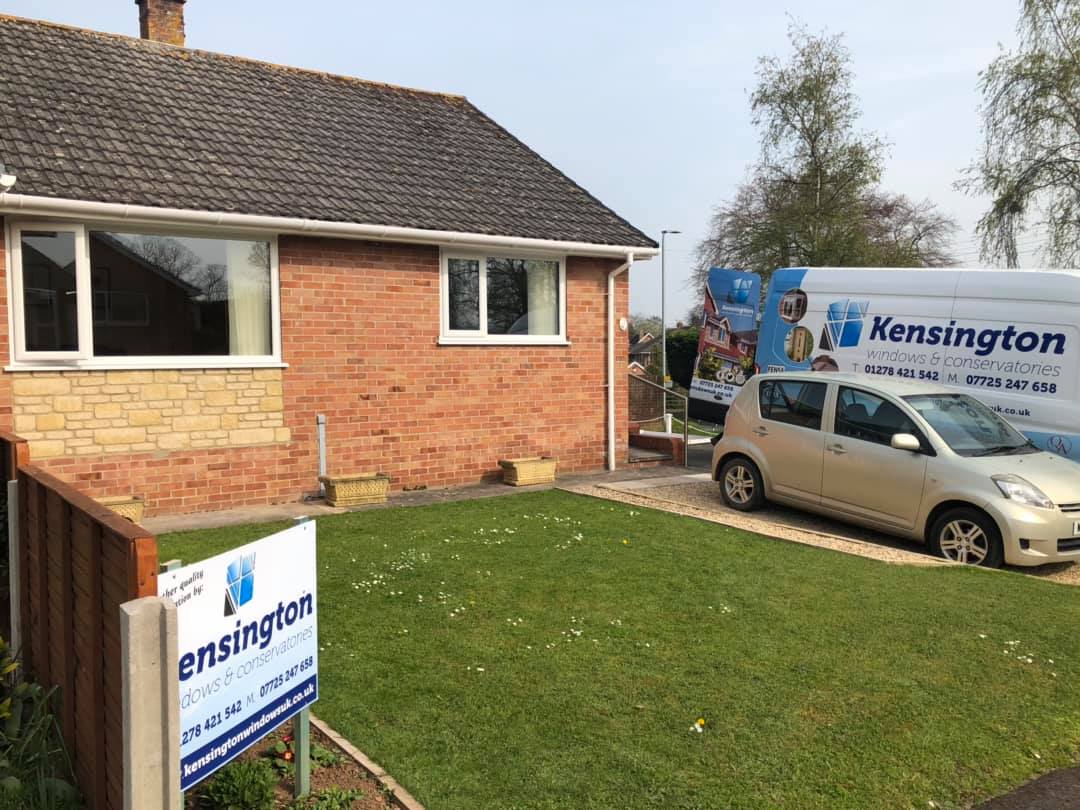 A car is parked in front of a house with a sign in front of it.
