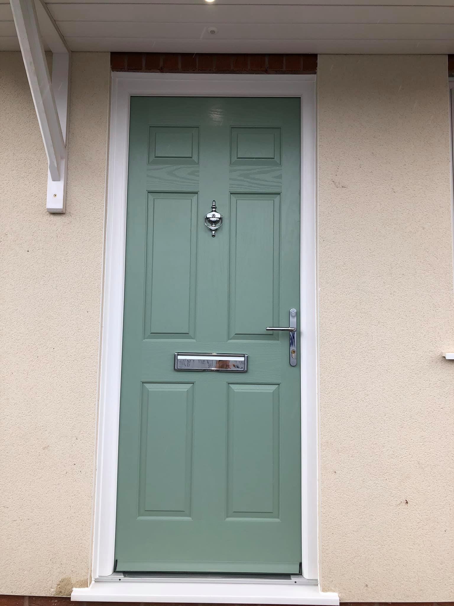 A green door is on the side of a house.