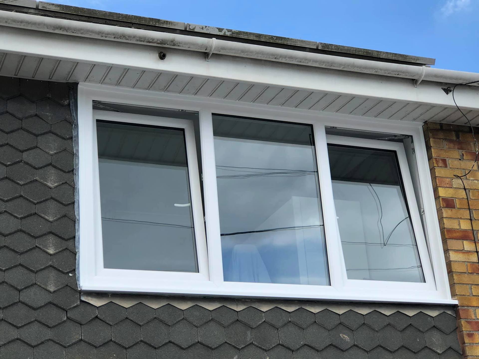 A white window is on the side of a brick building.