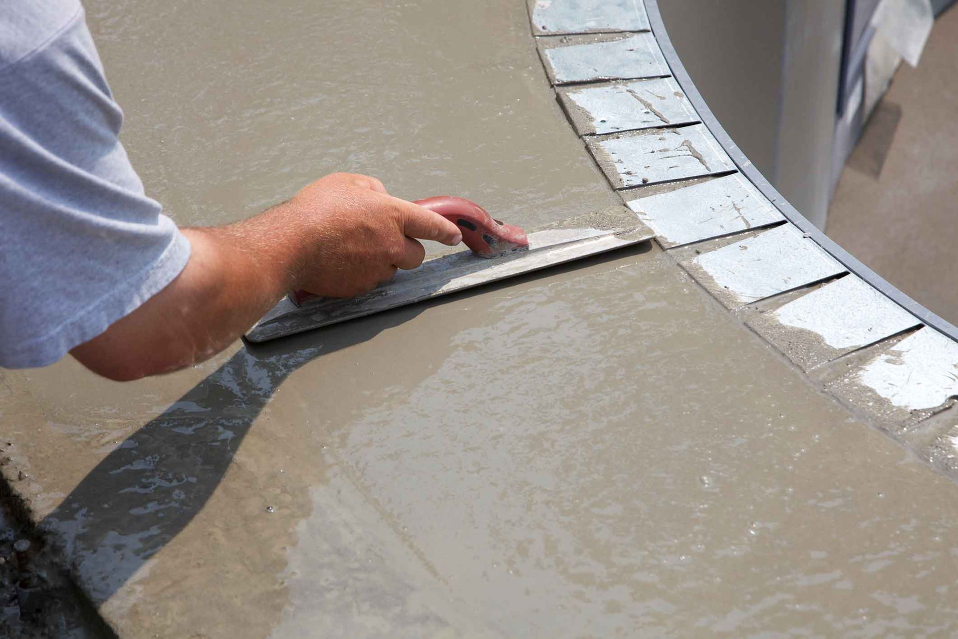 A man is using a trowel to spread concrete on a table.