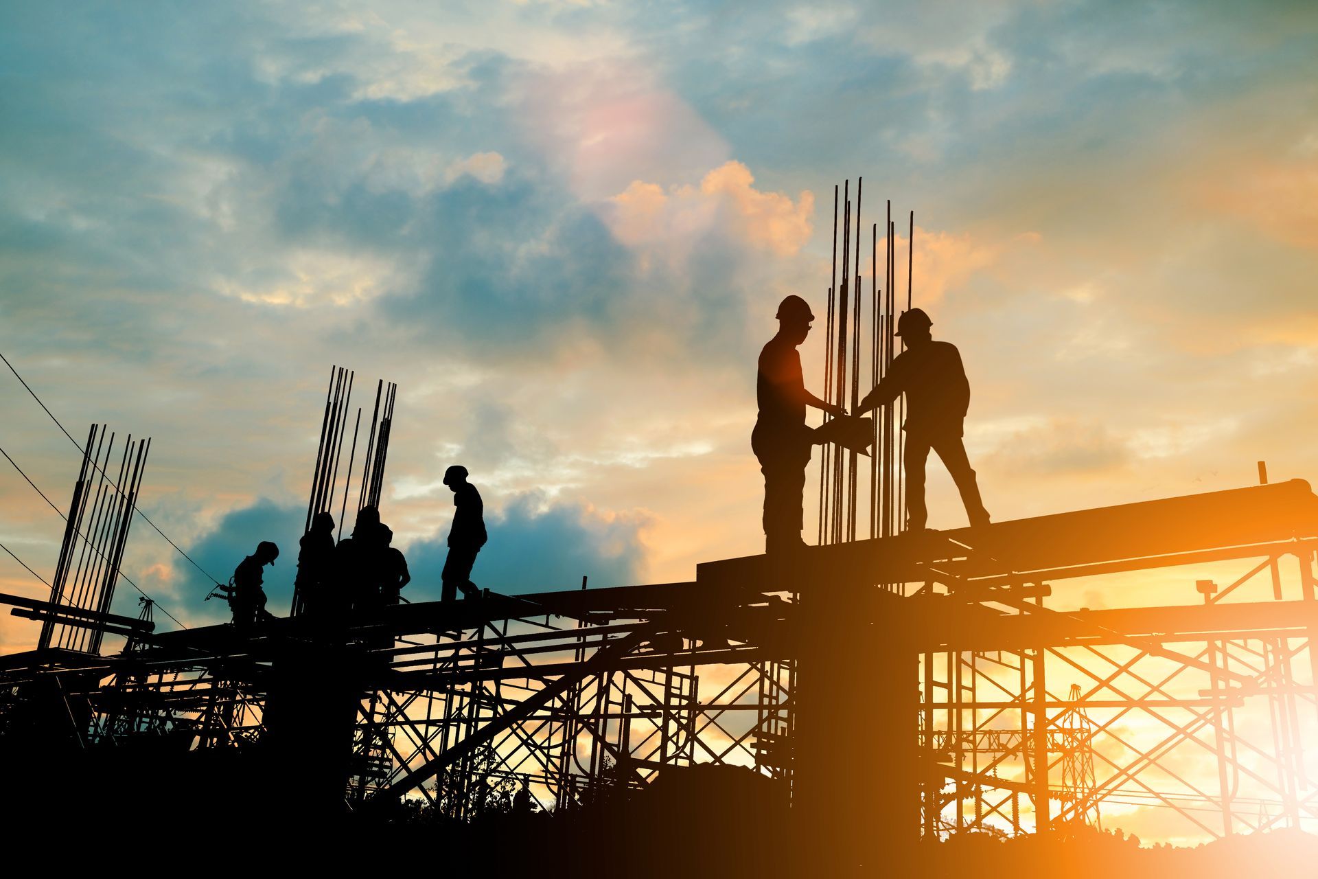 Silhouette of civil contractors at the site over a blurred background sunset.