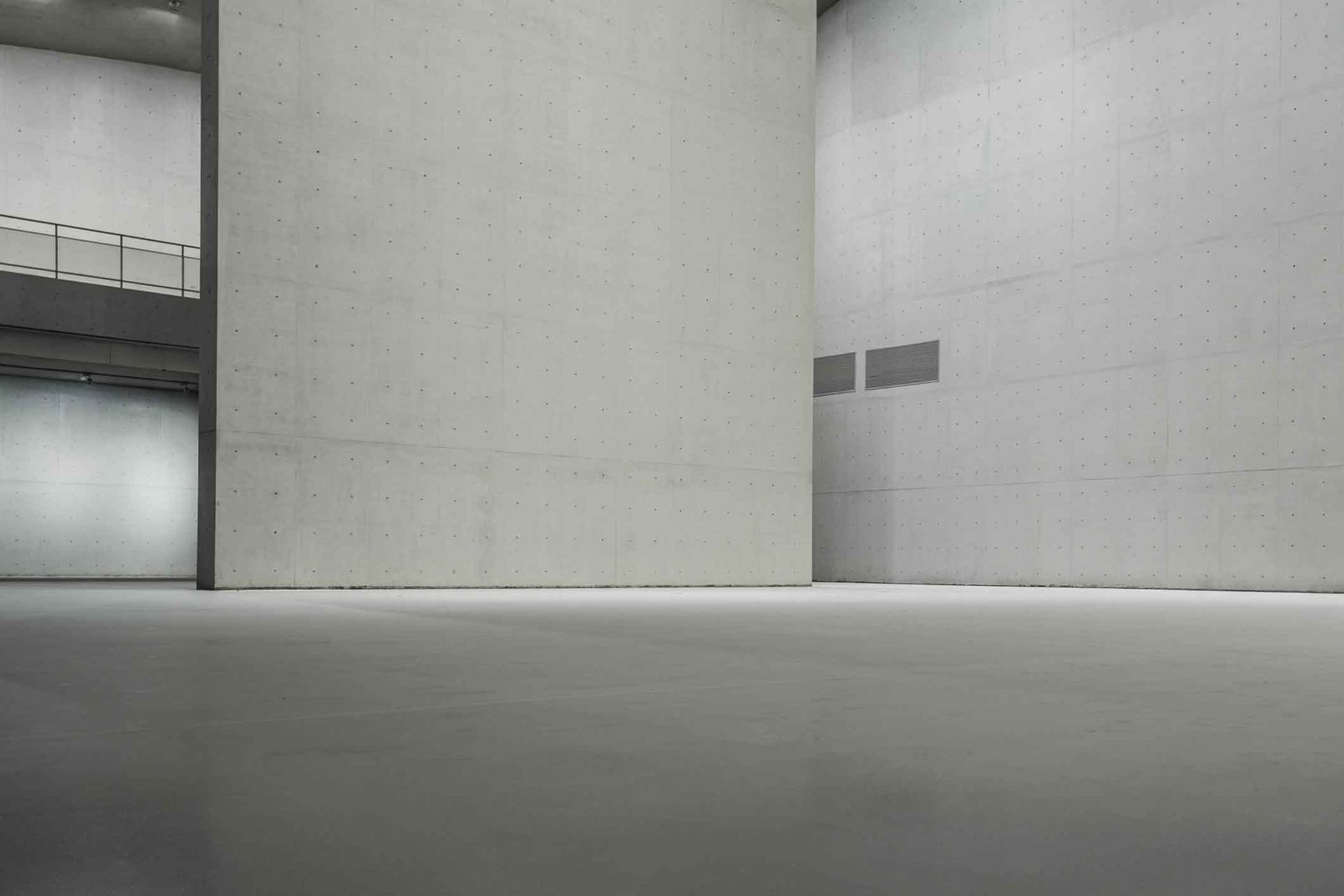A large empty room with concrete walls and a staircase.