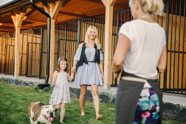 A woman and child walking towards a dog shelter worker with a bulldog.