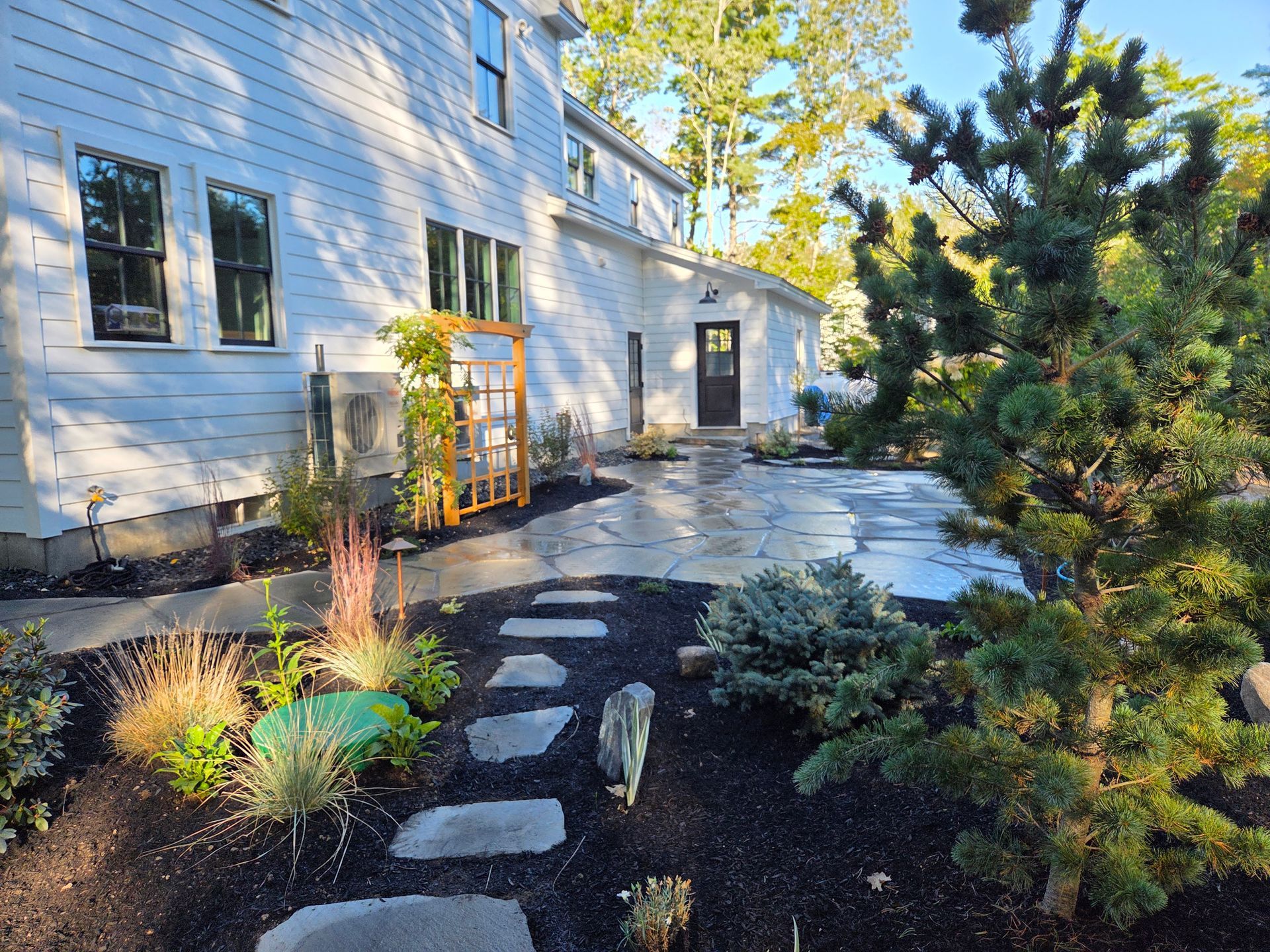 Backyard patio with flagstone path, lush landscaping, and white house.