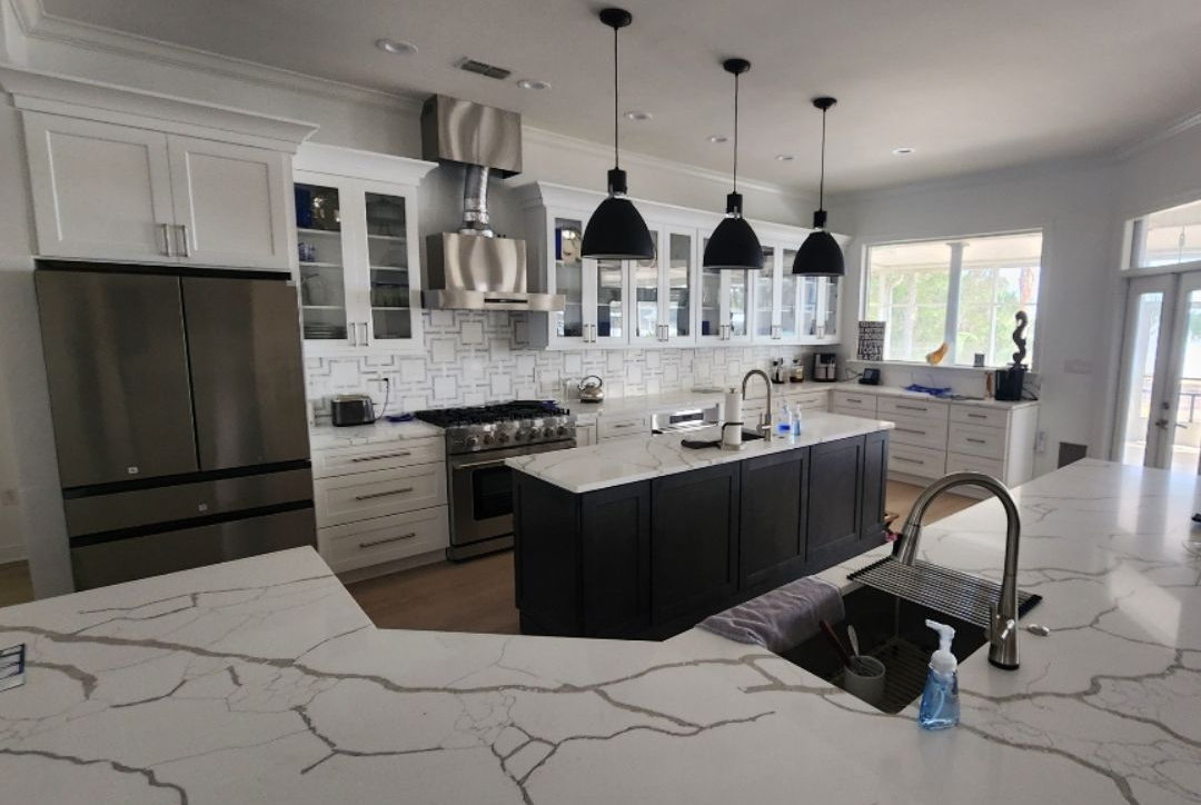 Modern kitchen with white and dark cabinets, stainless steel appliances, and island with black base.