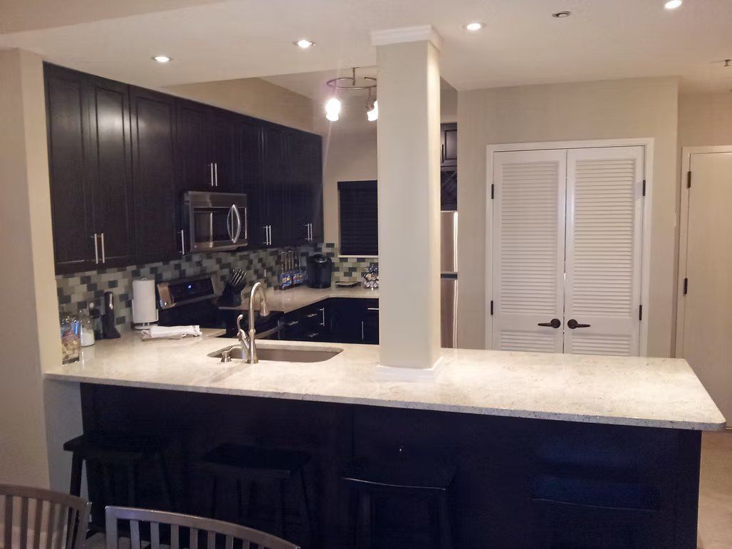 Kitchen with dark cabinets, light countertops, and white shutter doors.