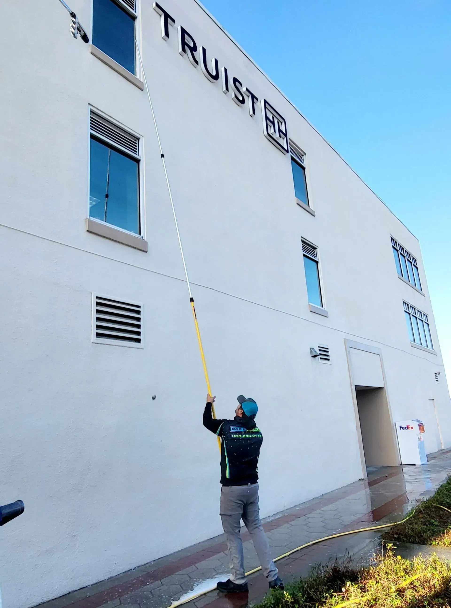 A man is cleaning the side of a building with a hose.