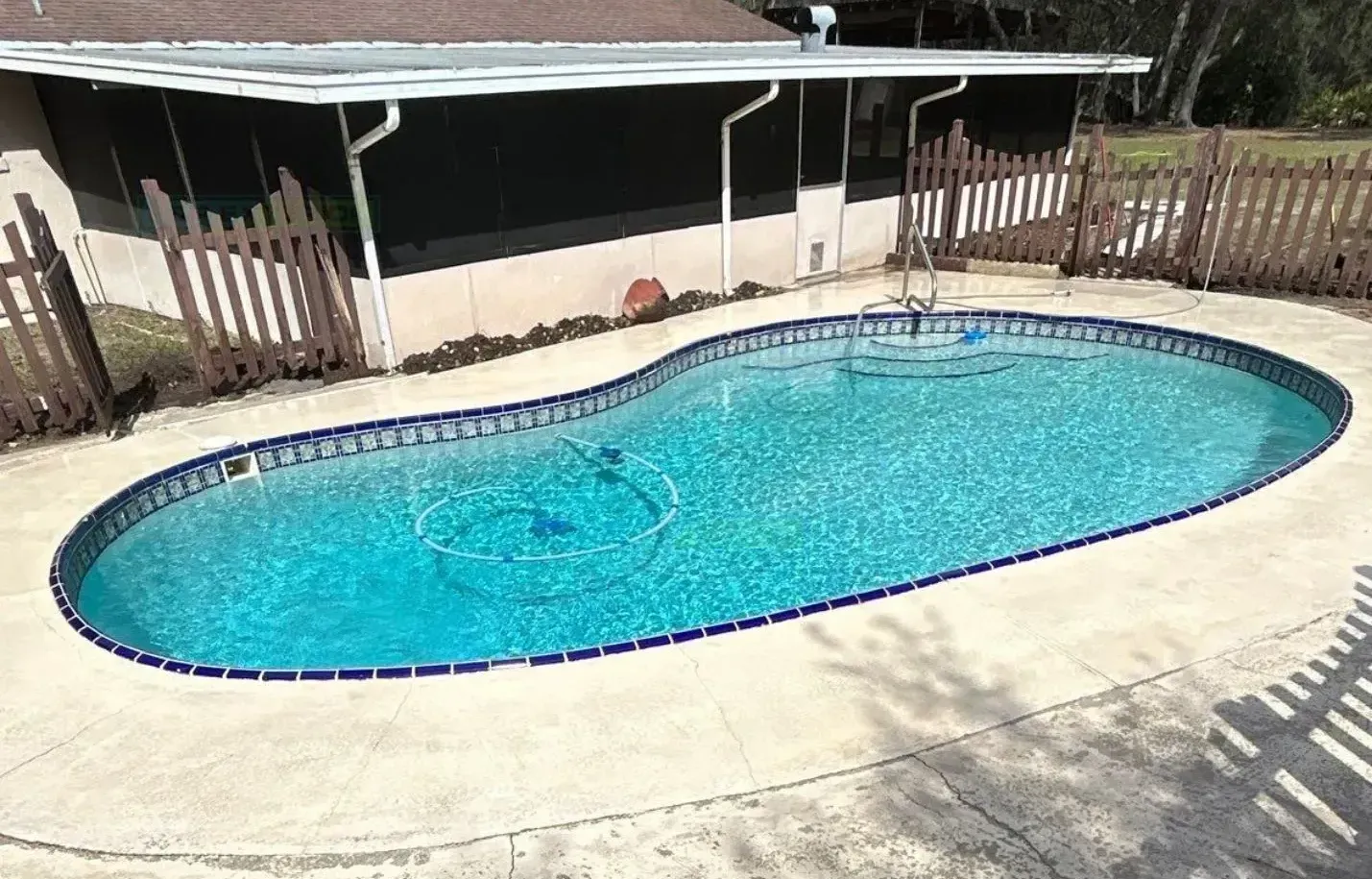A large swimming pool is sitting in front of a house.