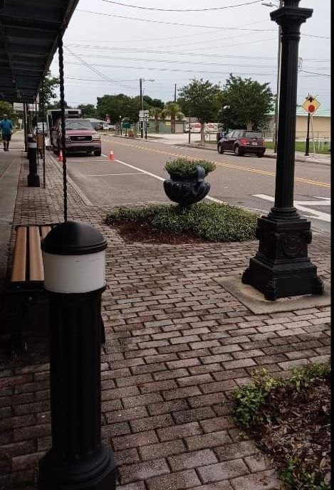A brick sidewalk with a bench and a lamp post