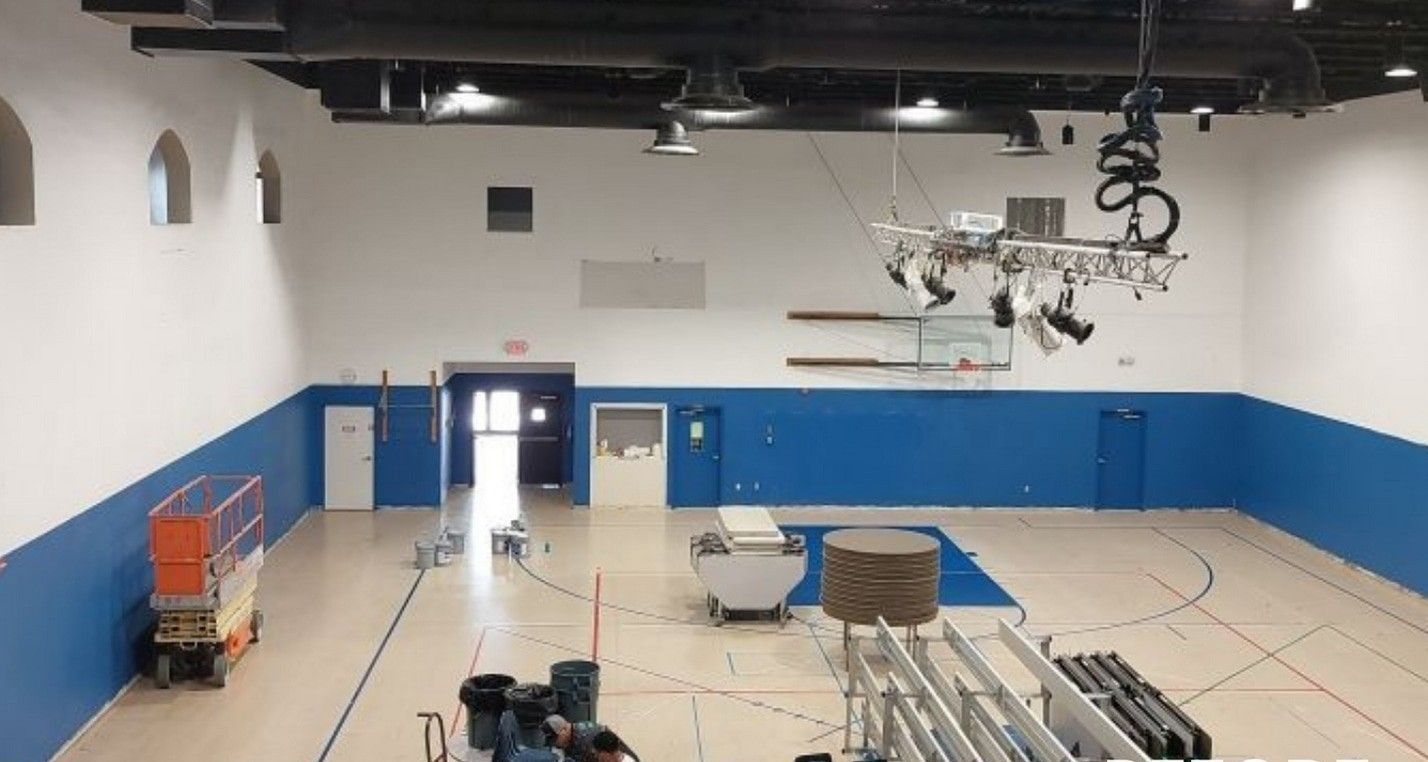 An empty gym with blue and white walls and a basketball hoop