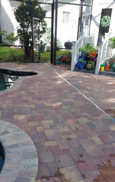 A brick patio with a swimming pool in the background.
