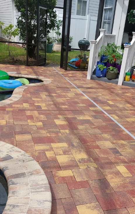 A brick patio with a swimming pool in the background.