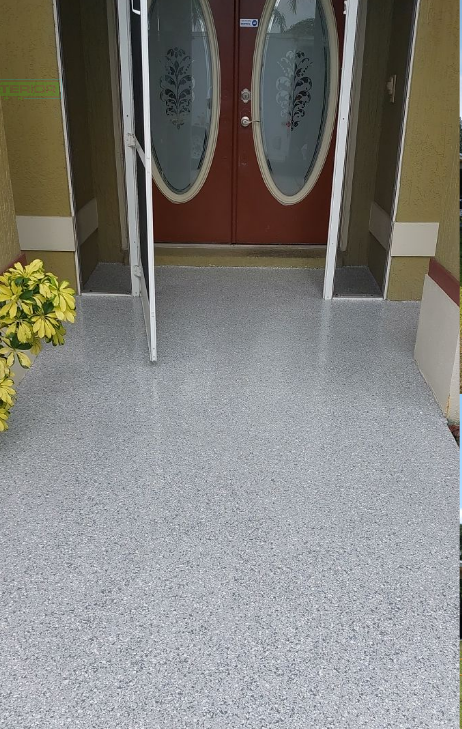 The front door of a house with a concrete floor and a red door.