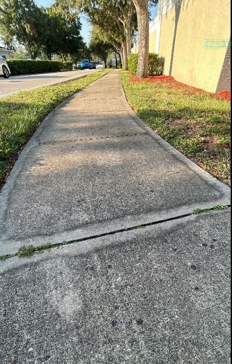 A sidewalk with a curb and grass on the side of it.