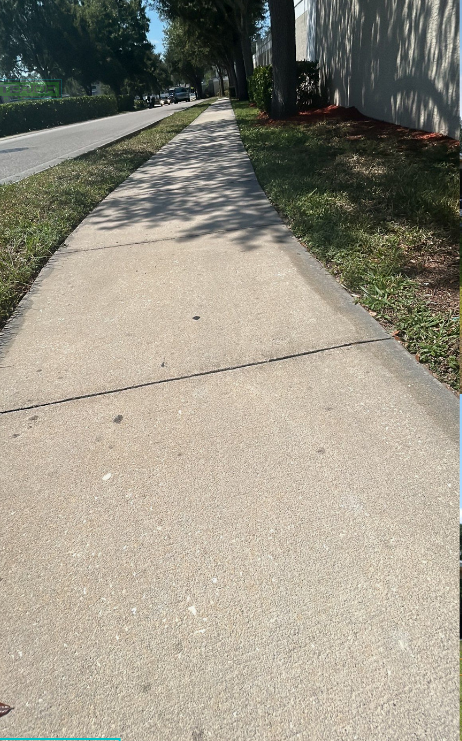 A concrete sidewalk with grass on the side of it