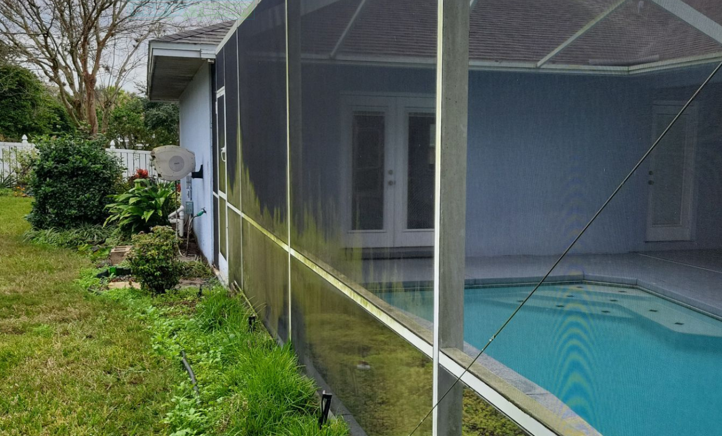 A screened in porch with a swimming pool in the background.