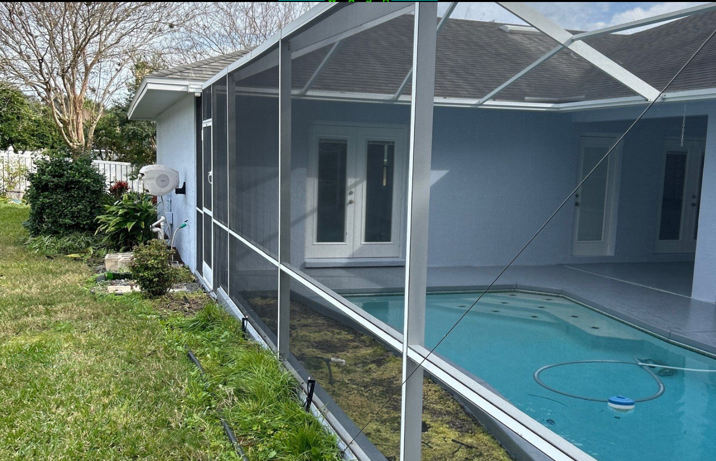 A screened in porch with a swimming pool in the background.